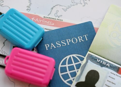 Passport and visa with boarding pass tickets and toy luggage bags on world map close up
