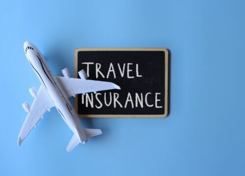 Top view image of toy plane and chalkboard with text TRAVEL INSURANCE on blue background.